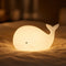 Veilleuse bébé baleine en silicone en ambiance cosy sur textile doux